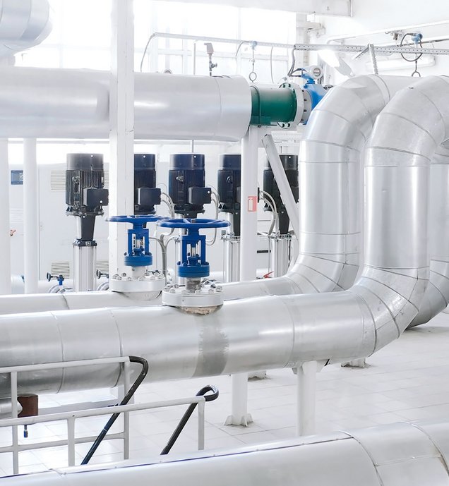 Halle mit verzweigten Metallrohren, blauen Ventilen und modernen Pumpensystemen