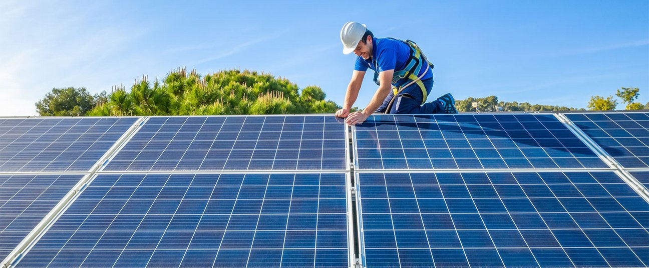Das Bild zeigt einen Handwerker, der eine PV-Anlage auf dem Dach installiert.