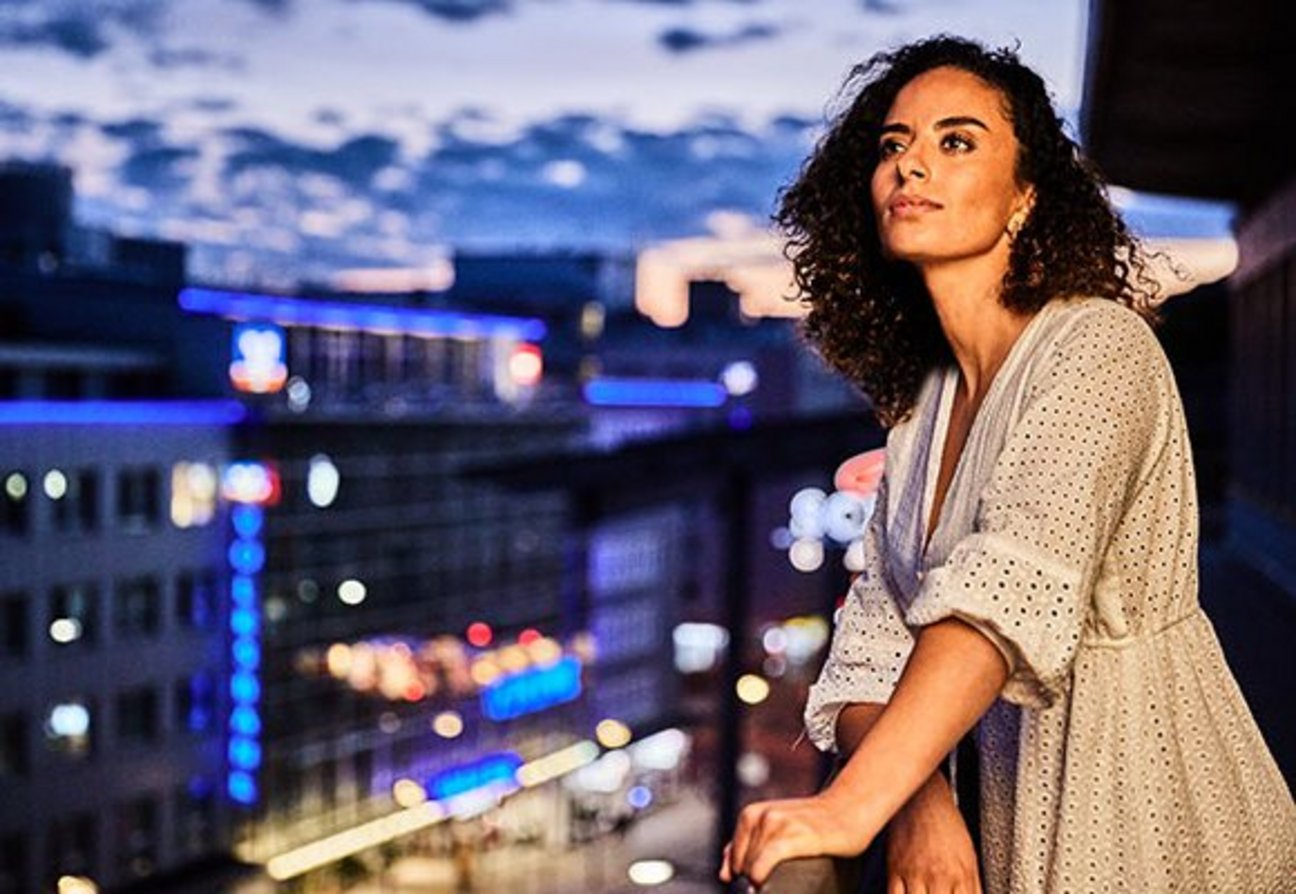 Das Bild zeigt eine junge Frau, die den Ausblick über Pforzheim bei Nacht genießt.