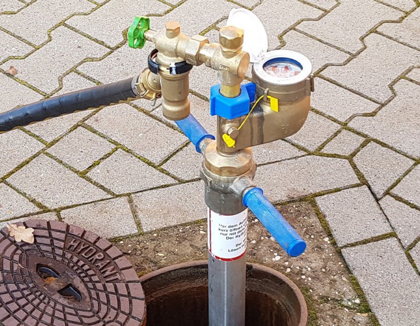 Hydrant mit montiertem Standrohr und Wasserzähler im öffentlichen Bereich