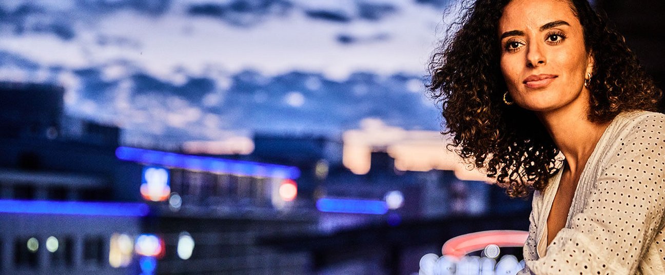 Das Einstiegsbild zeigt eine Frau die auf ein Pforzheim bei Nacht herunterblickt.