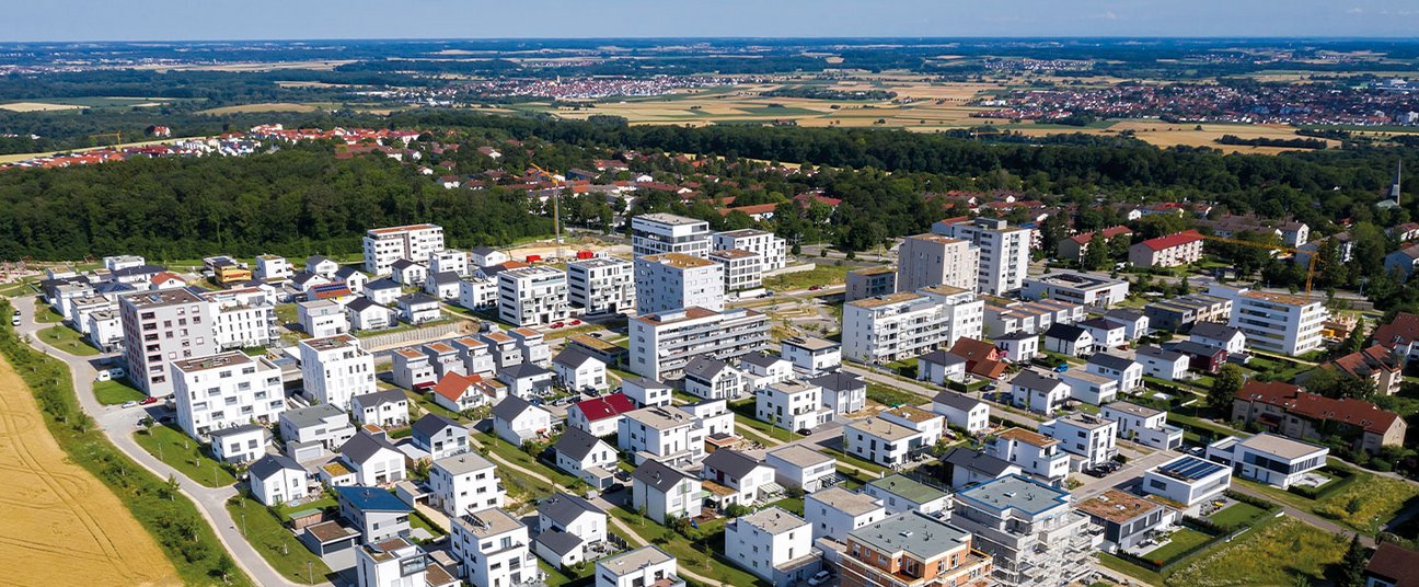 Das Einstiegsbild zeigt ein Gemeindequartier im Grünen.