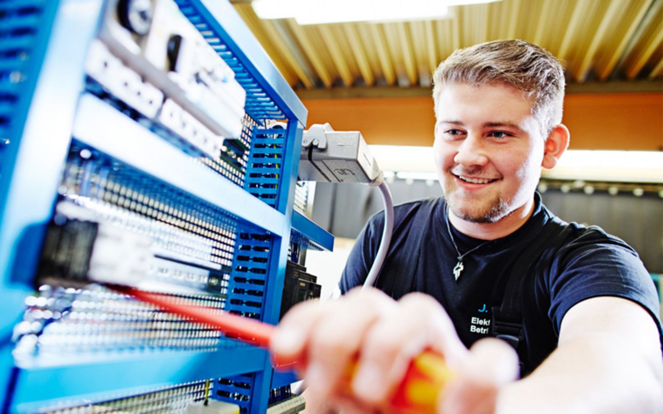 Das Bild zeigt einen Azubi, der mit elektrischen Geräten arbeitet.