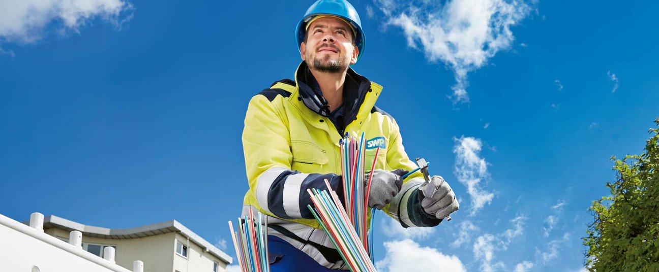 Das Einstiegsbild zeigt einen Handwerker, der Glasfaserkabel verlegt.