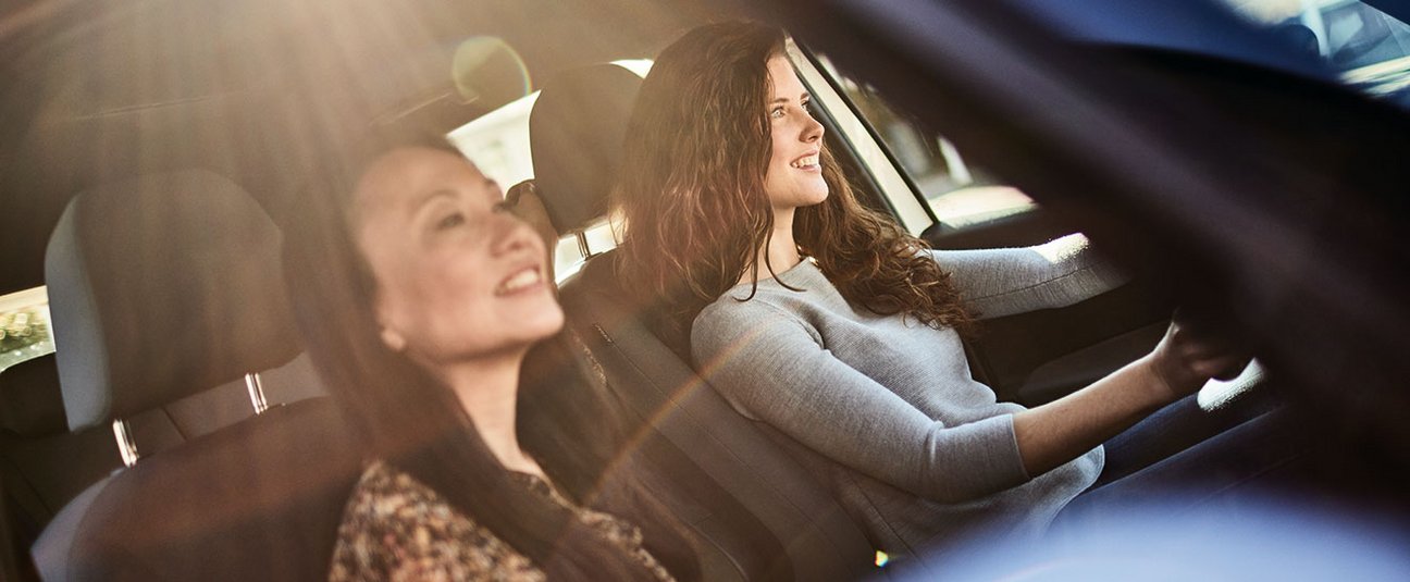 Das Bild zeigt zwei Frauen die in einem E-Auto fahren.