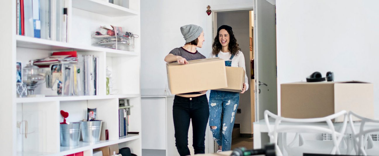 Das Einstiegsbild zeigt 2 junge Frauen beim Umzug. Beide haben Kisten in der Hand.