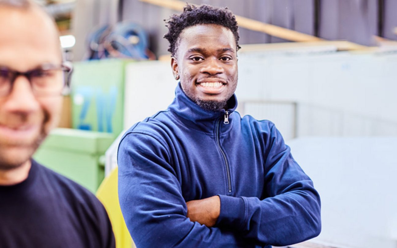 Das Bild zeigt einen jungen Mann der stolz in die Kamera lächelt. 