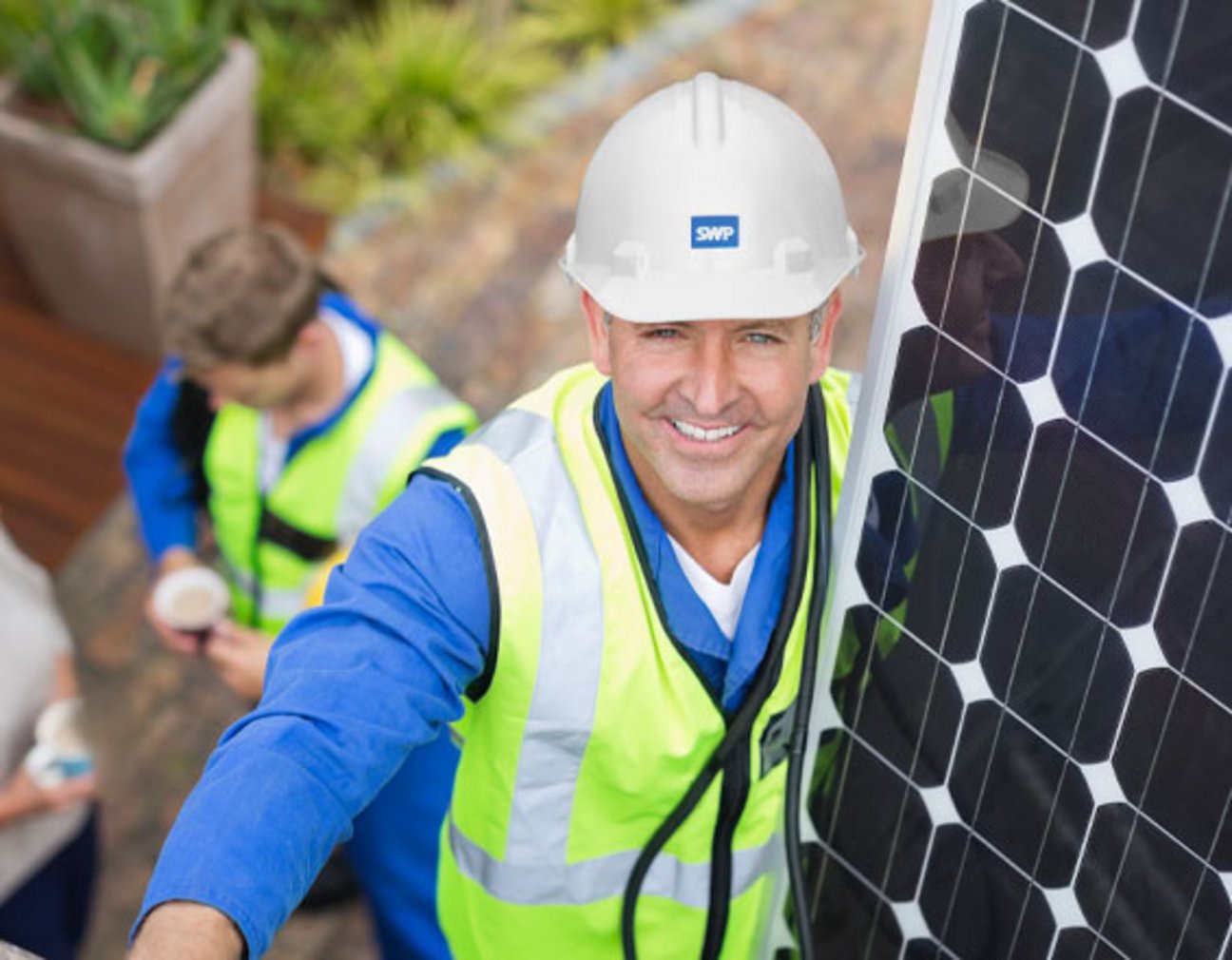 Das Bild zeigt einen Handwerker mit einer PV-Anlage, der in die Kamera lächelt